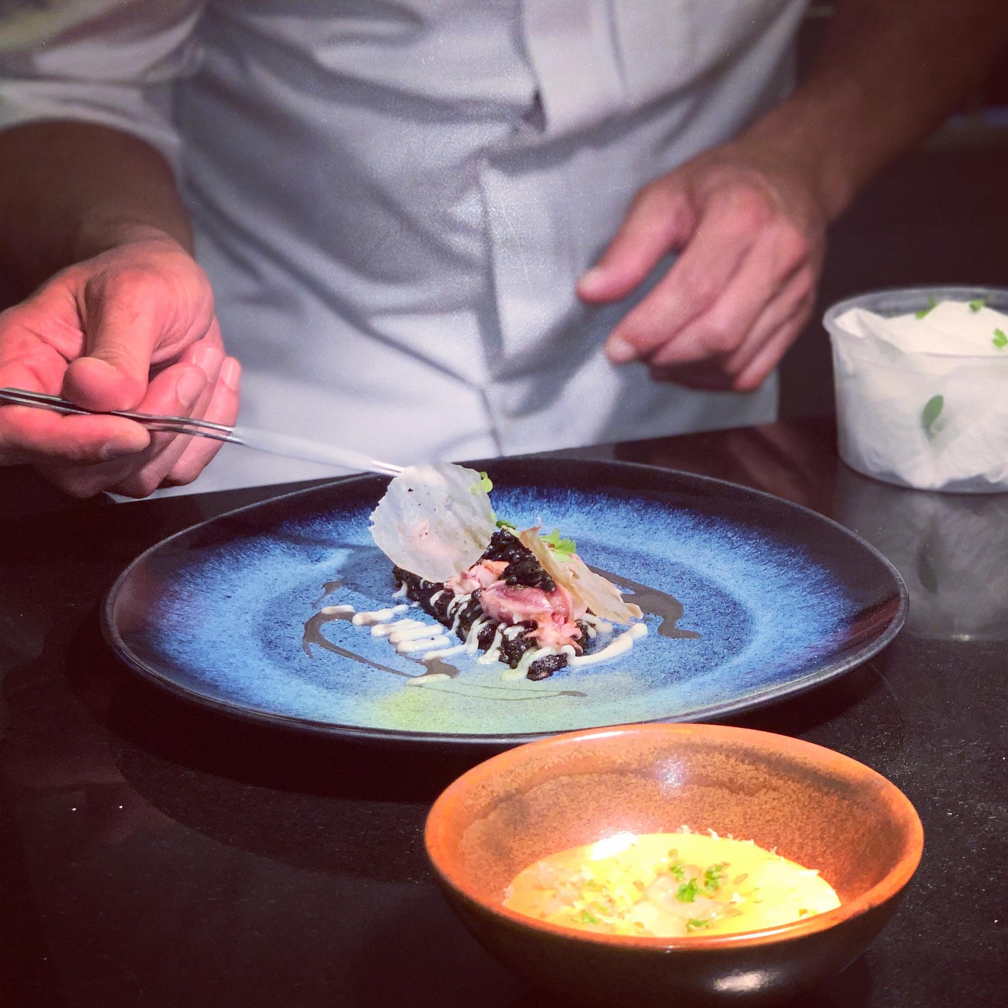 Chef demonstrating technique with a plated dish